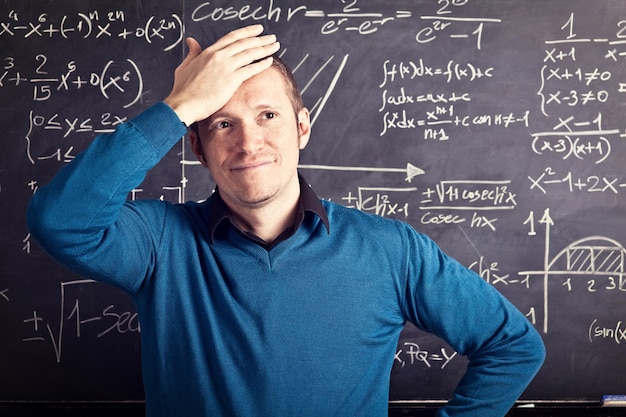 Foto frustreerde leraar staat tegen het bord in de klas.