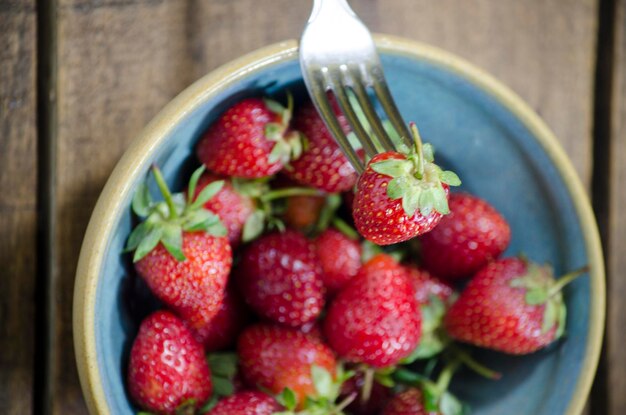 Photo frutillas frescas sobre bowl ceramica y fondo madera