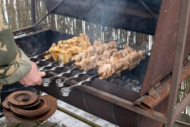 串に刺したさまざまな種類の肉のシシカバブをグリルの人間の手で揚げる