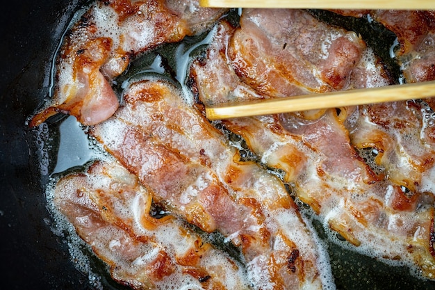 Frying bacon in a preheated pan Top view