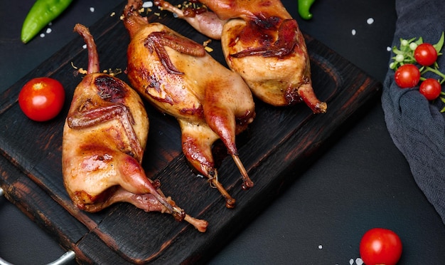 Frying carcasses of quails lie on a wooden board with vegetables