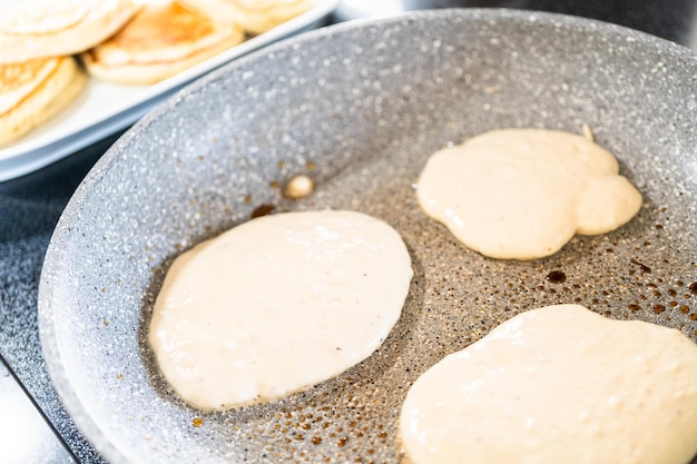 Frying kefir based pancakes in cooking pan on an electric\
stove.