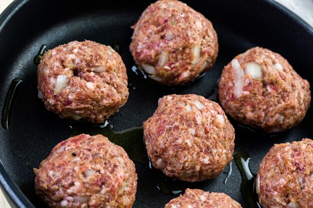 Frying large homemade Italian meatballs on a midium frying pan for dinner.