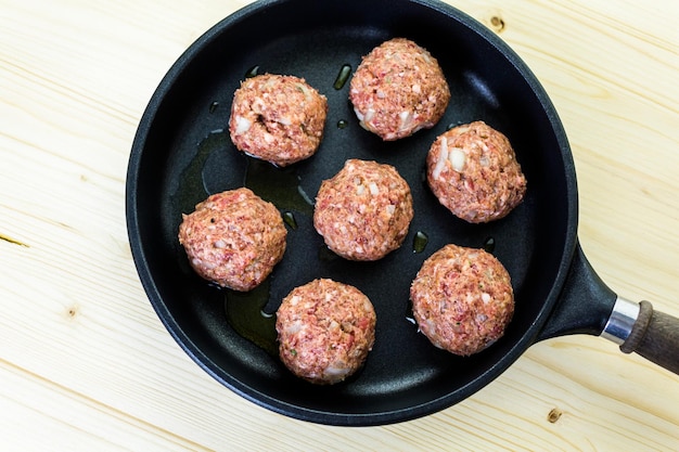 Frying large homemade Italian meatballs on a midium frying pan for dinner.