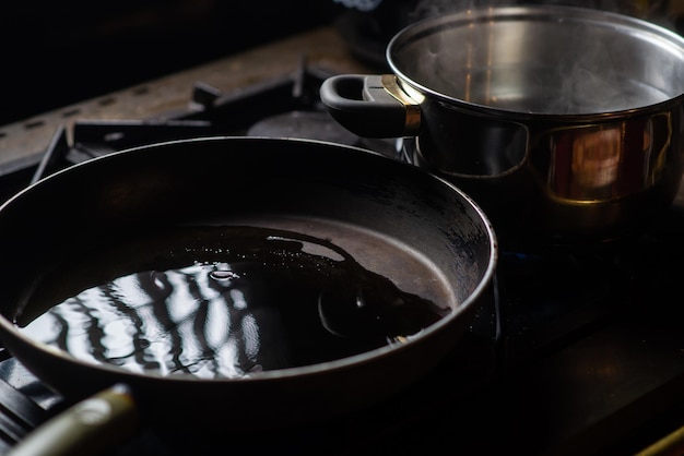 Foto una padella piena d'olio e una pentola d'acqua sul fornello preparazione per la cottura stoviglie