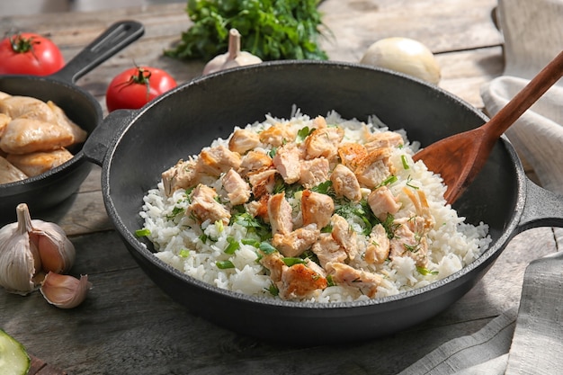 Frying pan with chicken and rice on kitchen table