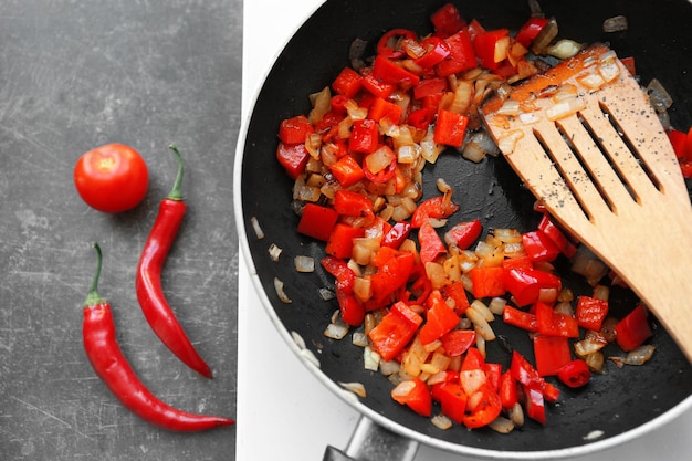 Frying pan with chopped onion and pepper on hot plate