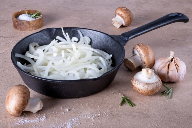 A frying pan with chopped onions stands on a dark surface