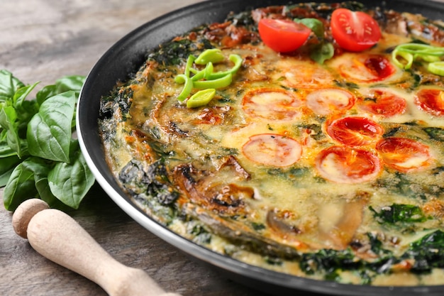 Frying pan with delicious spinach frittata on table closeup