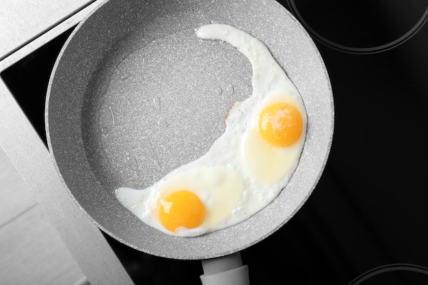 Photo frying pan with eggs on stove