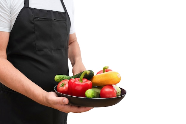 Frying pan with fresh vegetables in the hands of a cook isolated on a white background cooking conce