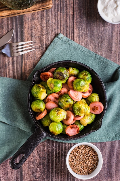 Frying pan with fried sausages and Brussels sprouts Homemade food Top and vertical view