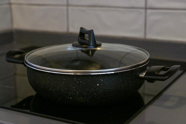 Frying pan with glass lid on the glassceramic hob of a kitchen