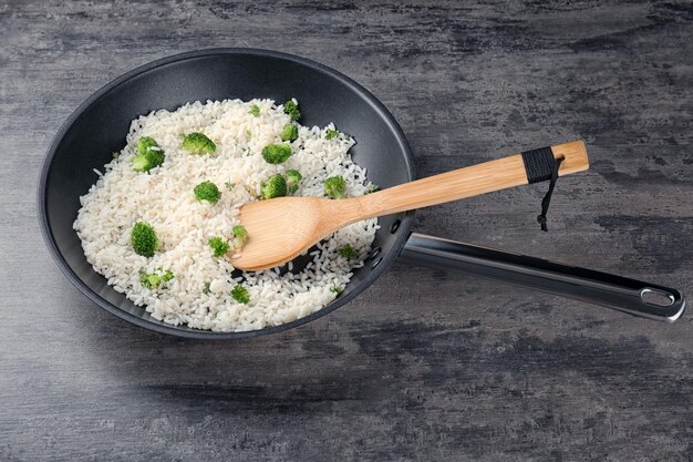 Photo frying pan with rice and broccoli on table