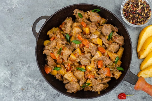 Frying pan with stew, quince and vegetables. Studio Photo.