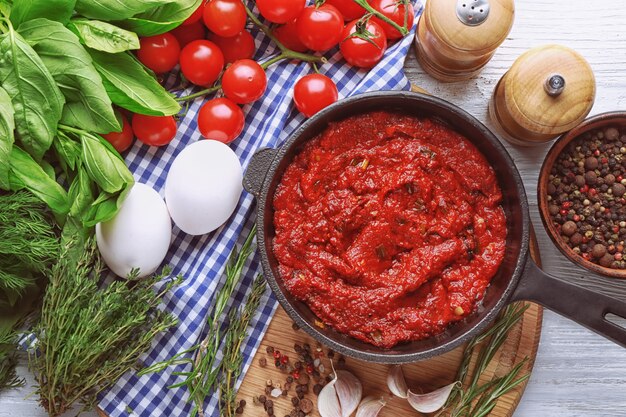 Frying pan with tasty spicy sauce on table