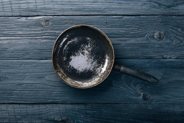 Photo frying pan on a wooden black background top view free space for your text