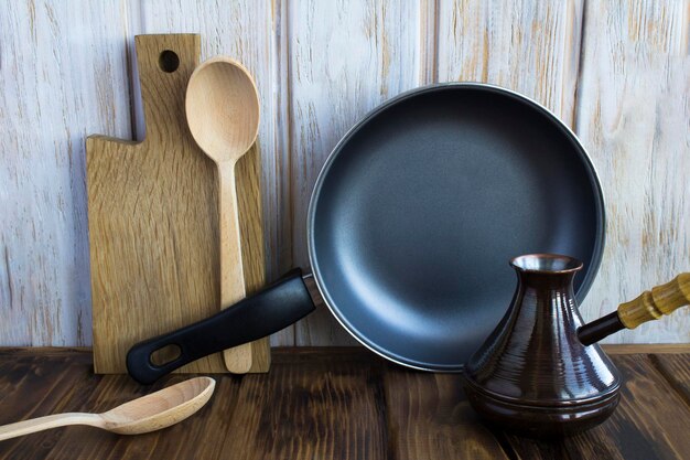 Frying pan and wooden utensils on the rustic wooden backgrondCloseup