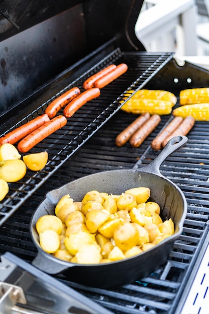 Frying small golden potatoes in cast iron skillet an outdoor gas grill.