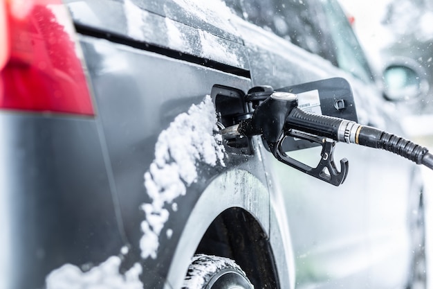 Fuel pistol left inside the car during petrol or gasoline refull at the station in freezing winter time.