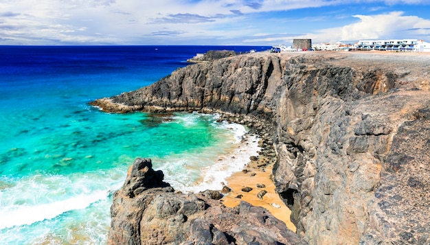 写真 フェルテベントゥラ島-エルコティージョの岩の多いビーチとトストンタワーの眺め。カナリア諸島