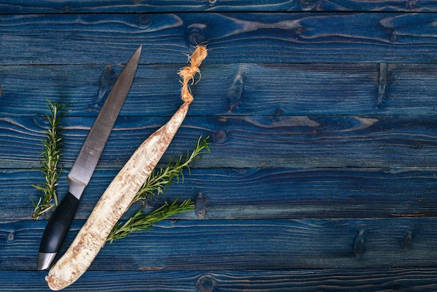 Photo fuet salami and rosemary traditional spanish sausage on a blue wooden background top view