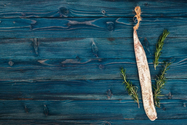 Foto fuet salame e rosmarino salsiccia tradizionale spagnola su sfondo di legno blu vista dall'alto