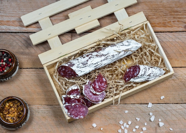 Fuet sausage cut in slices with spices on a rustic wooden table