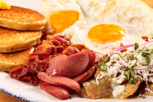 Full American breakfast with eggs, bacon, pancakes, sausage and chilaquiles, food