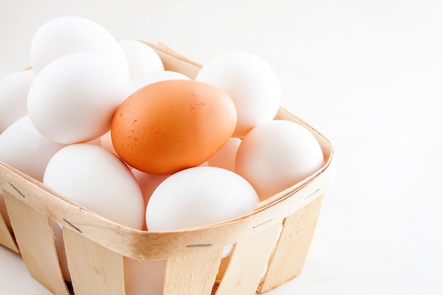Полная корзина свежих яиц на белом фоне