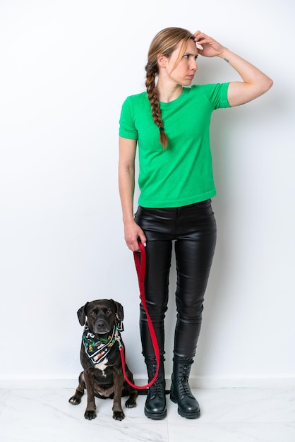 Full body of girl with her puppy isolated on white background having doubts and with confuse face expression