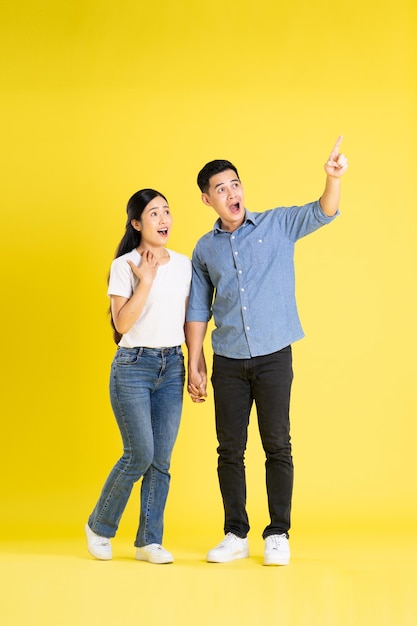 Full body image of asian couple posing on yellow background