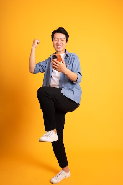 Full body image of asian man posing on yellow background