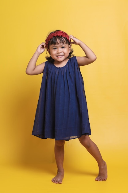 Full body image of beautiful asian baby girl touching her hair and smiling