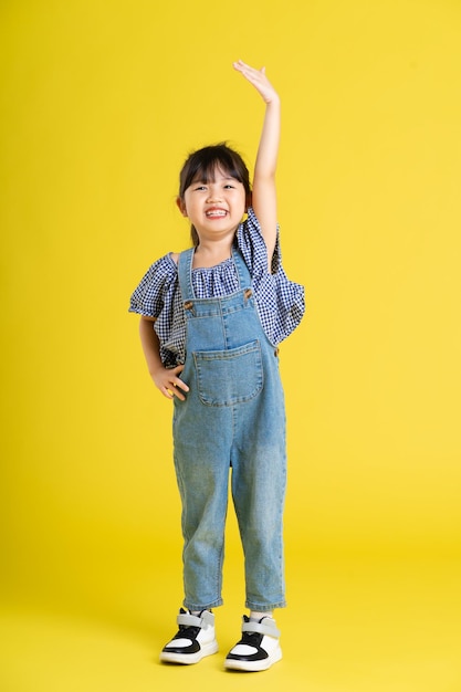 Full body image of beautiful asian baby girl on yellow background