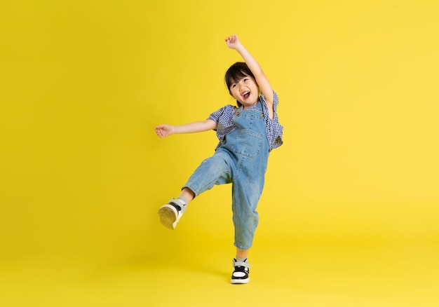 Full body image of beautiful asian baby girl on yellow background