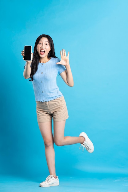 Full body image of beautiful asian girl posing on blue background