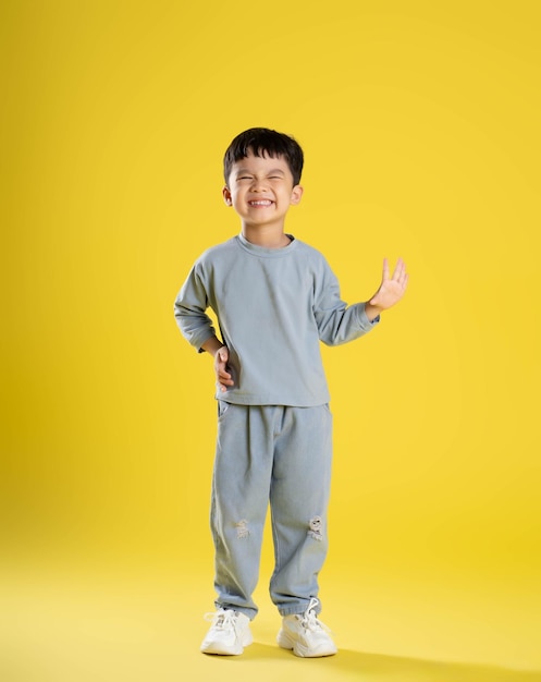 Full body image of boy posing on a yellow backgroundxA