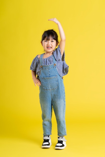 사진 노란색 배경에 아름다운 아시아 여자 아기의 전신 이미지
