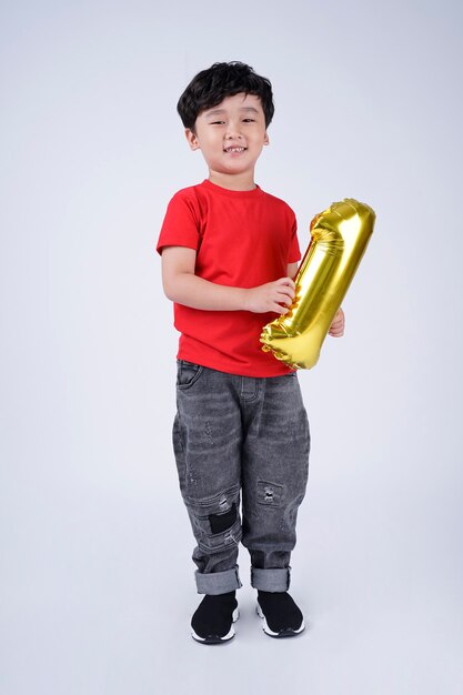 Tutta la lunghezza del corpo di un bambino asiatico felice sorriso con palloncino numero di alluminio, isolato