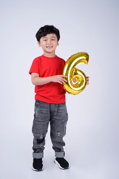 Full body length of Asian little kid happy smile with foil number balloon, isolated