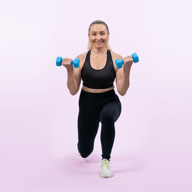 Full body length shot active and sporty senior woman lifting dumbbell during weight training workout on isolated background Healthy active physique and body care lifestyle for pensioner Clout