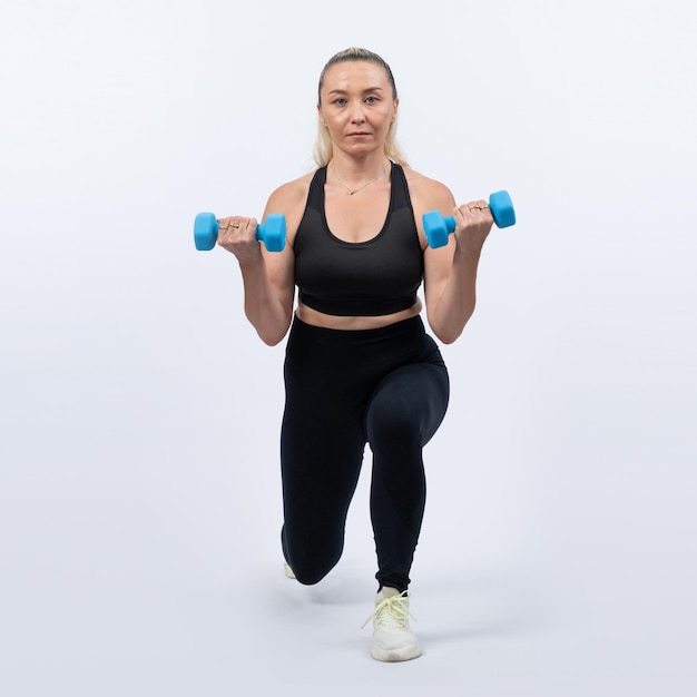 Full body length shot active and sporty senior woman lifting dumbbell during weight training workout on isolated background Healthy active physique and body care lifestyle for pensioner Clout