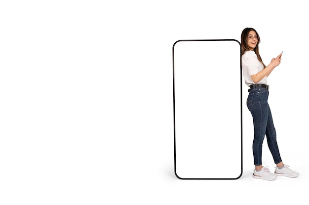 Full body length view woman leaning huge smartphone with empty blank screen mockup