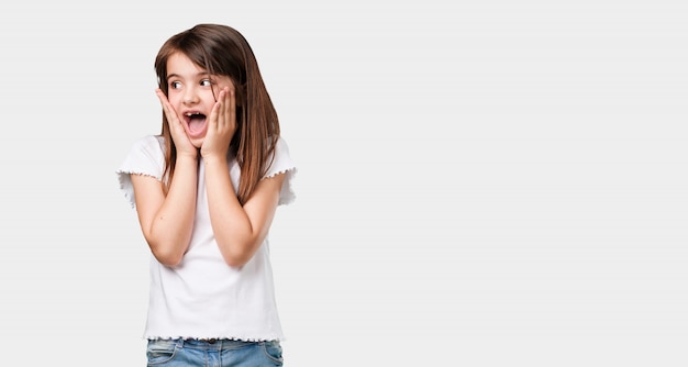 Full body little girl surprised and shocked, looking with wide eyes, excited by an offer or by a new job, win concept