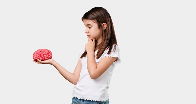 Foto bambina piena del corpo che pensa e che deduce, guardando un cervello che prova a capirlo