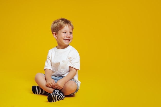 写真 白いカジュアルなtシャツを着た少年が笑顔で,テキストのための空きスペースを見ています.