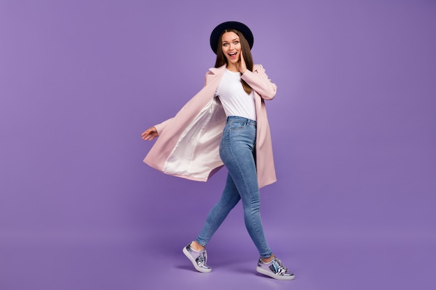 Full body photo of astonished positive crazy girl go walk look unbelievable bargains impressed scream touch hand face wear fall outfit isolated over violet color background