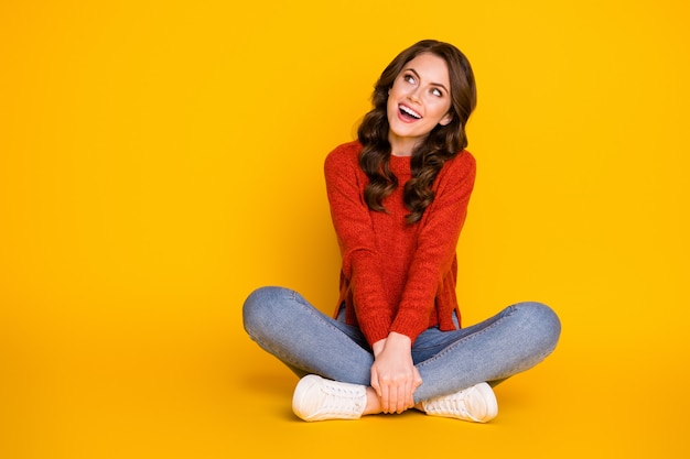 Full body photo of candid excited girl sit floor legs crossed look copyspace enjoy rejoice ads sales wear denim sweater isolated over shine color background