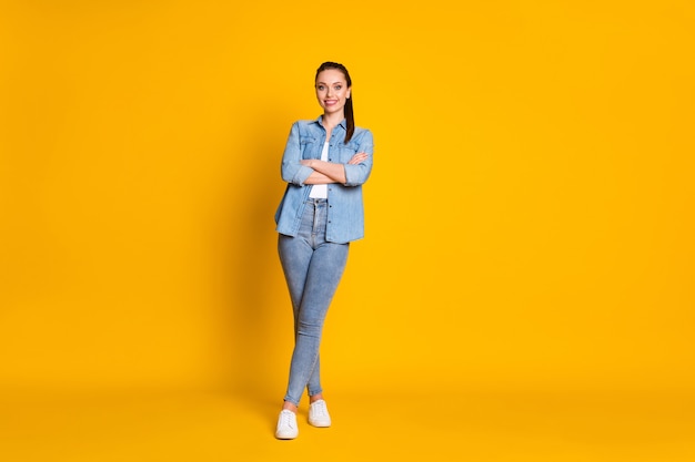 Foto di tutto il corpo di una ragazza affascinante e graziosa che incrocia le mani si diverte a lavorare indossando un bell'aspetto sneakers isolate su uno sfondo di colori vivaci